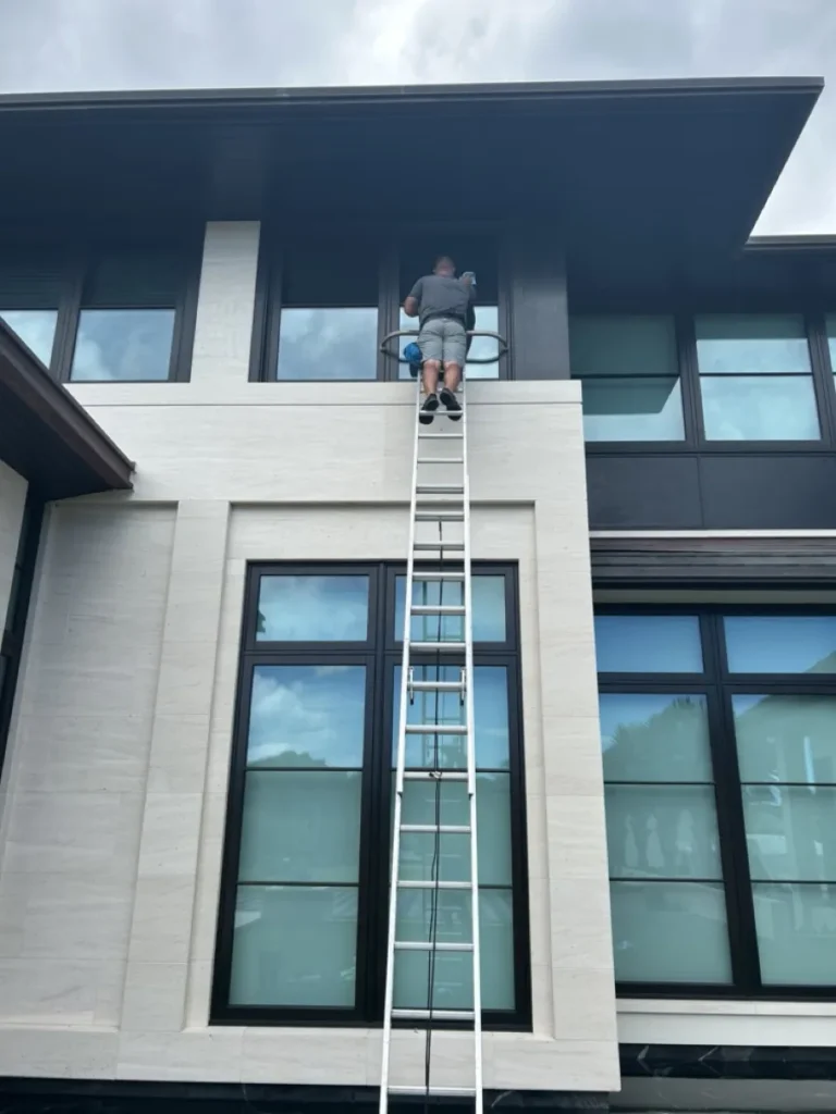 Window Solutions installer applying window film on a two-story home